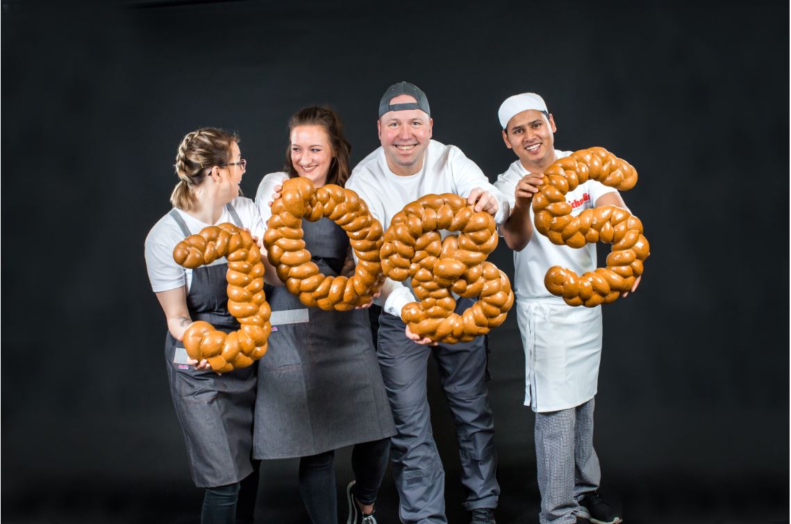 Vier Bäckerauszubildende mit Brot in der Hand