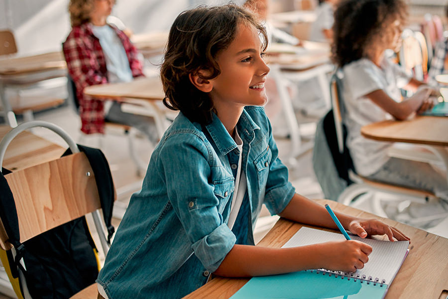 Schüler sitzt im Klassenraum und arbeitet an seinem Schulheft